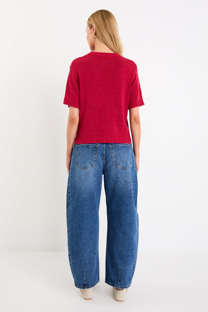 Model wearing a cherry red short sleeve knit tee with a crew neckline and side splits.