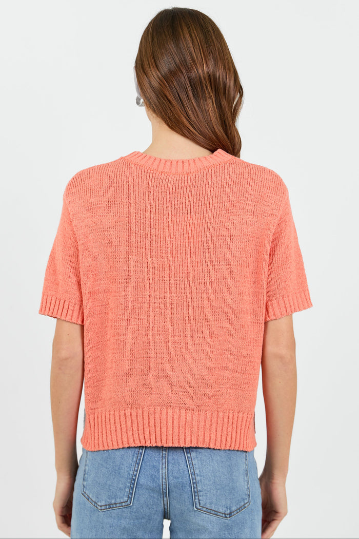 Back of a woman wearing a orange tee and blue jeans on a white background