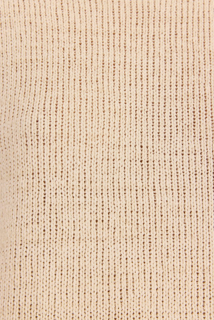 Close-up of a ribbed knit fabric in a warm cream or light beige color, showing the detailed vertical texture.