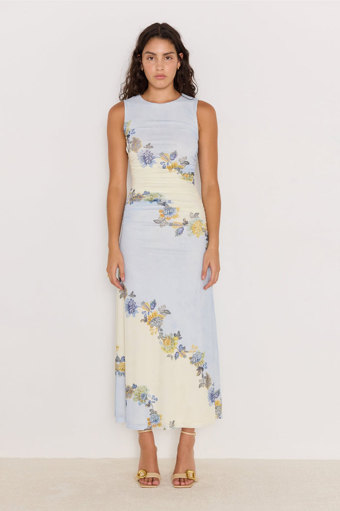 Woman wearing a sleeveless dress with floral pattern on a plain background