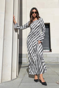 Woman wearing a full-length bias-cut dress with long sleeves and a diagonal charcoal stripe print, styled with black pointed heels.