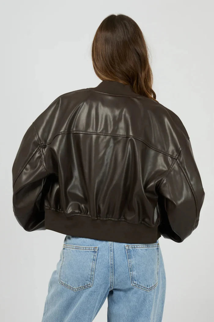 Person wearing a brown leather jacket and blue jeans on a plain background
col_pattern