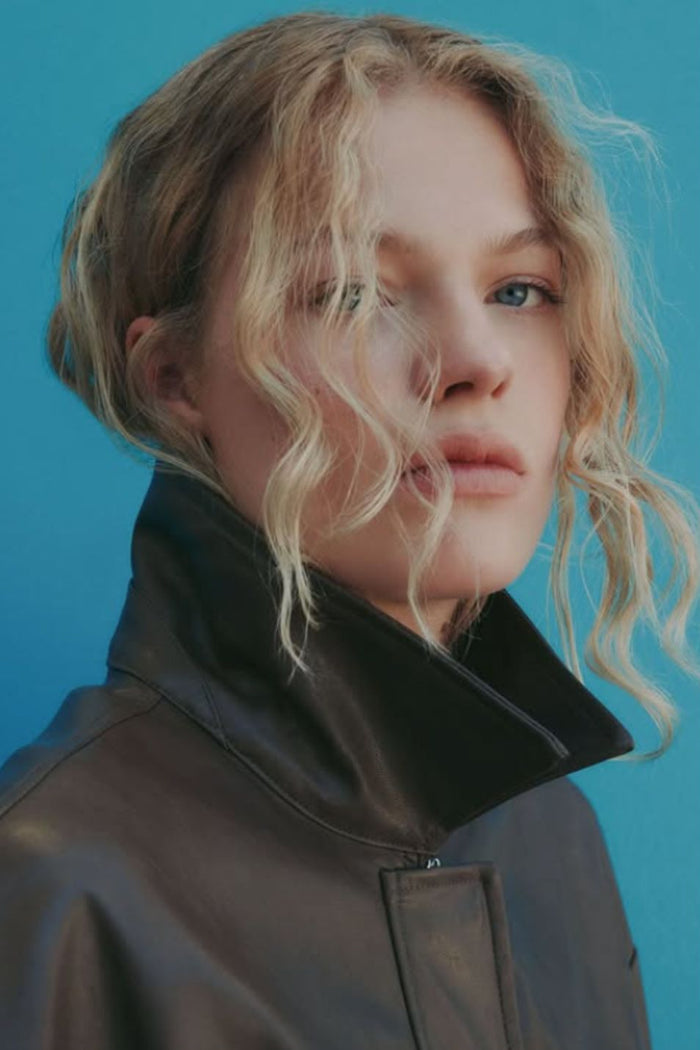 Person wearing a dark coat against a blue background