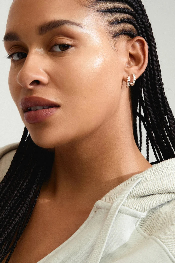 Woman with braided hair wearing a light-colored hoodie against a neutral background