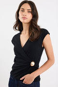 Woman wearing a black top with a gold button on a white background