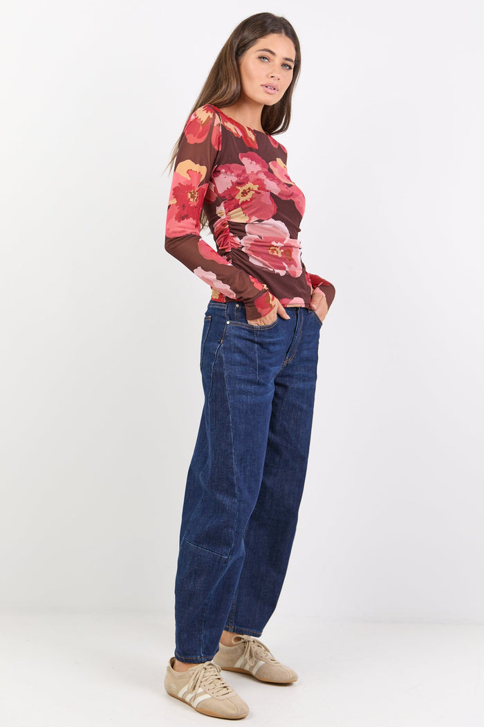 Woman wearing a floral top and blue jeans on a white background