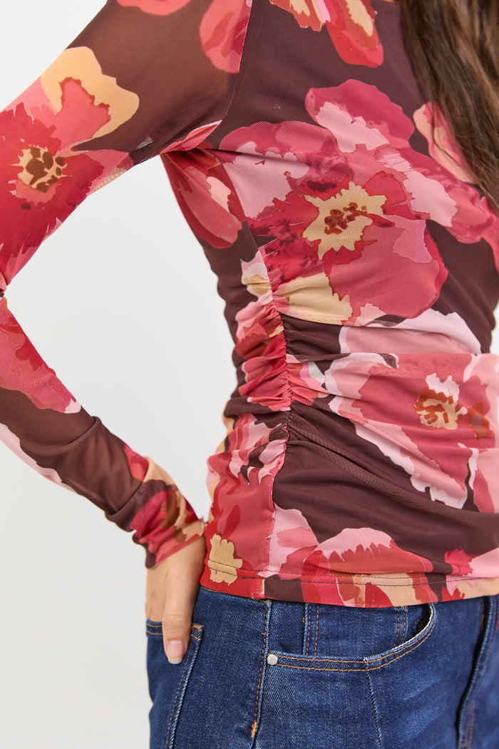 Floral long-sleeve top with ruched details on a plain background
