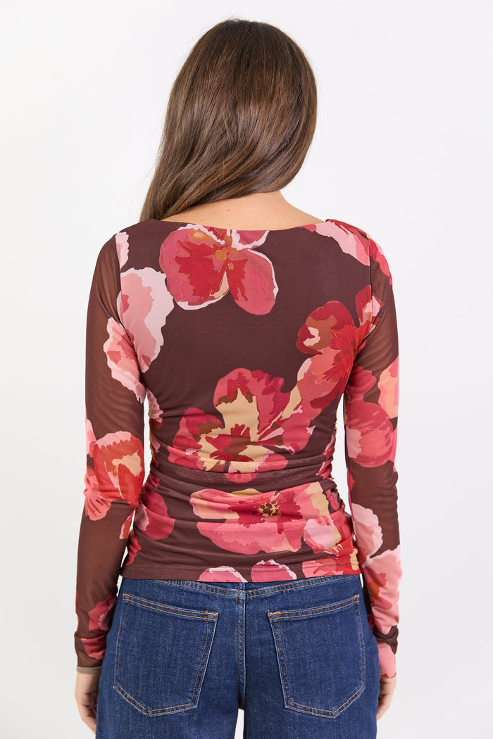 Woman wearing a long-sleeve top with pink floral pattern on a white background