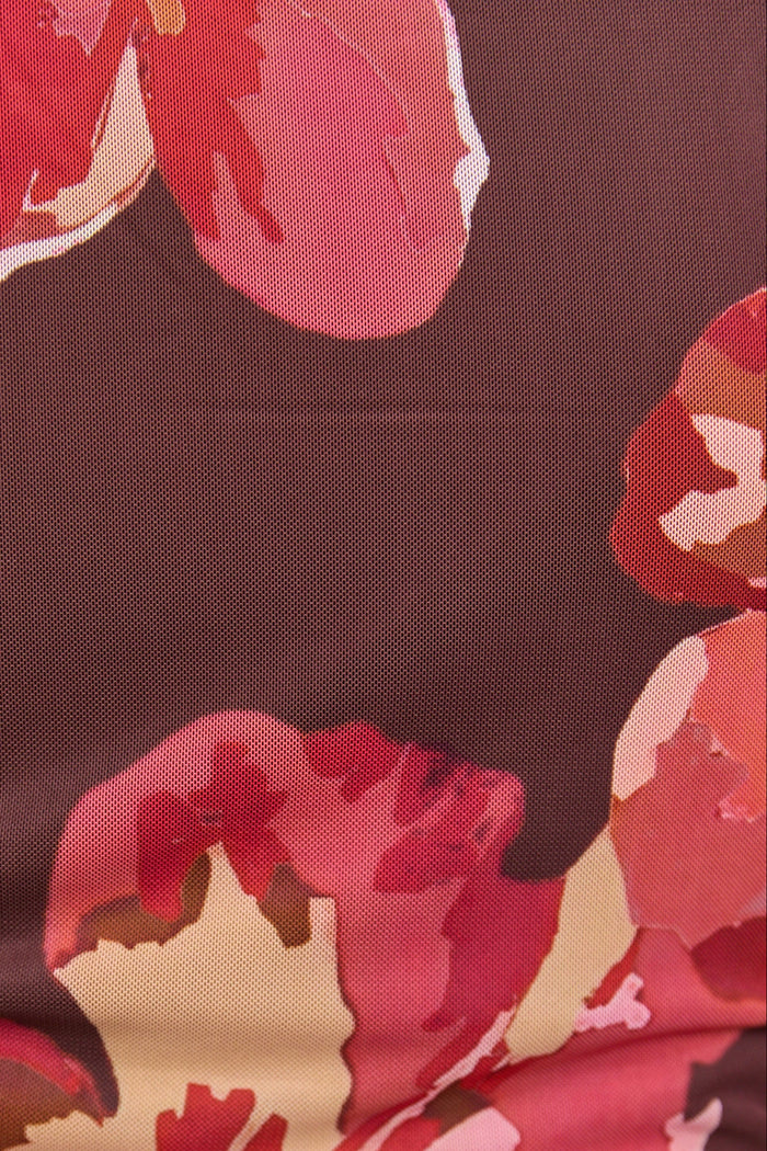 Close-up of a floral patterned fabric with pink and red flowers on a brown background.