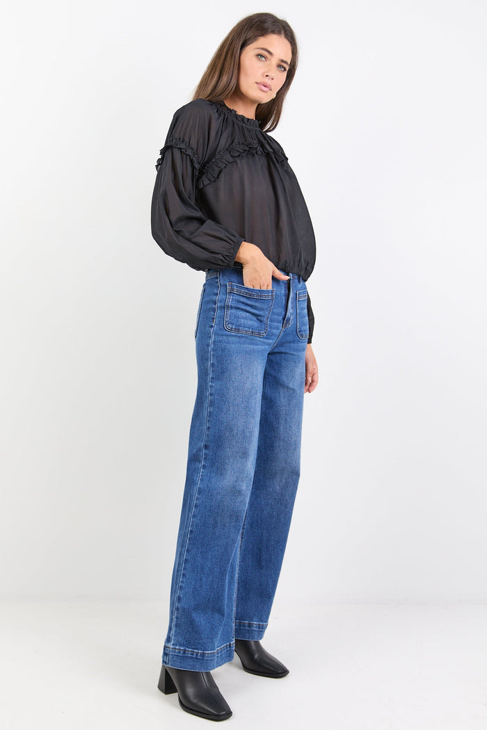 Woman wearing a black blouse and blue jeans on a white background