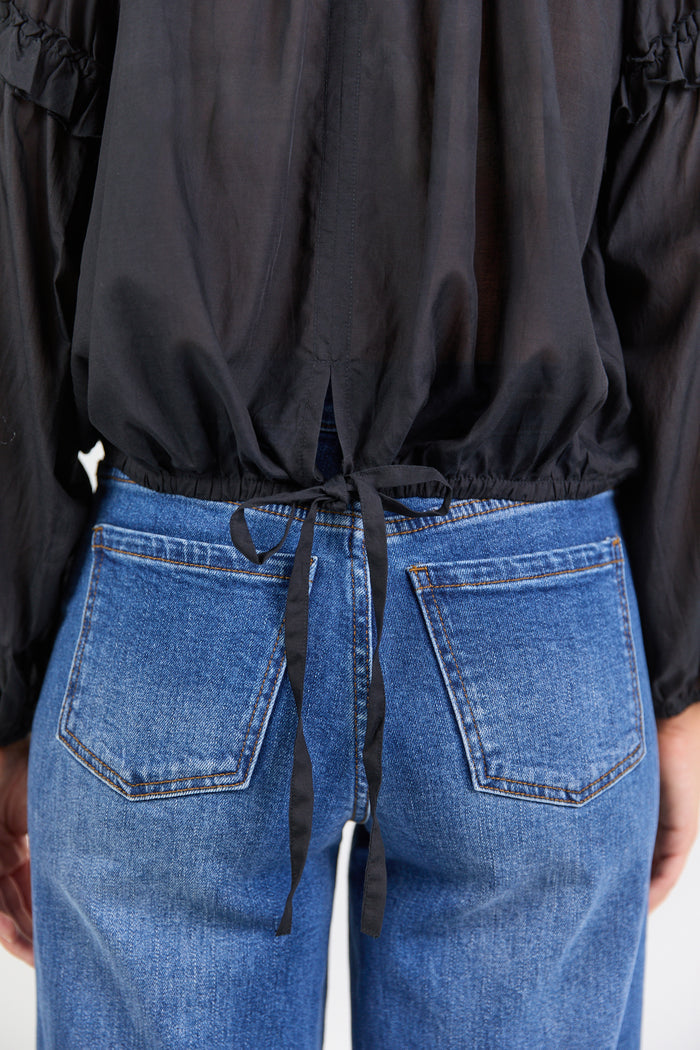 Person wearing a black top and blue jeans.