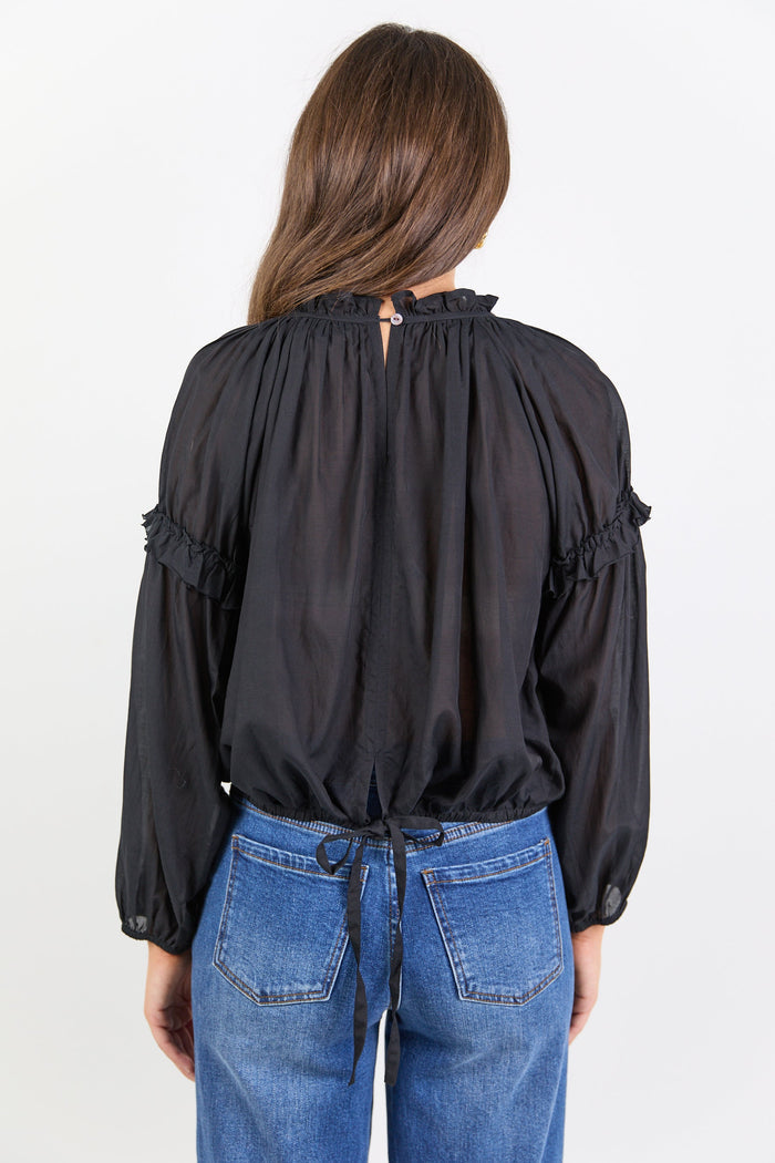 Person wearing a black blouse with long sleeves and blue jeans on a white background
