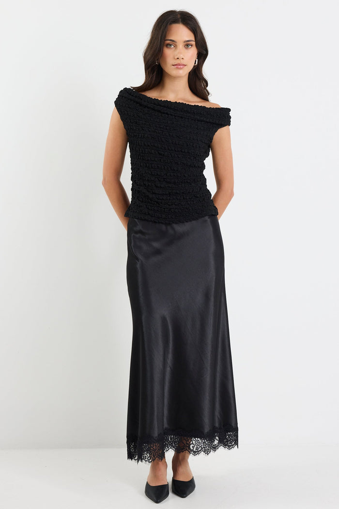 Woman wearing a black off-shoulder top and black skirt on a white background