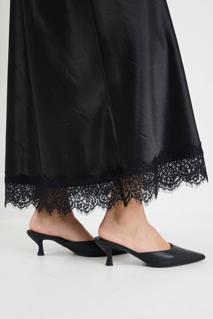 Black lace-trimmed pants with black high-heeled shoes on a white background