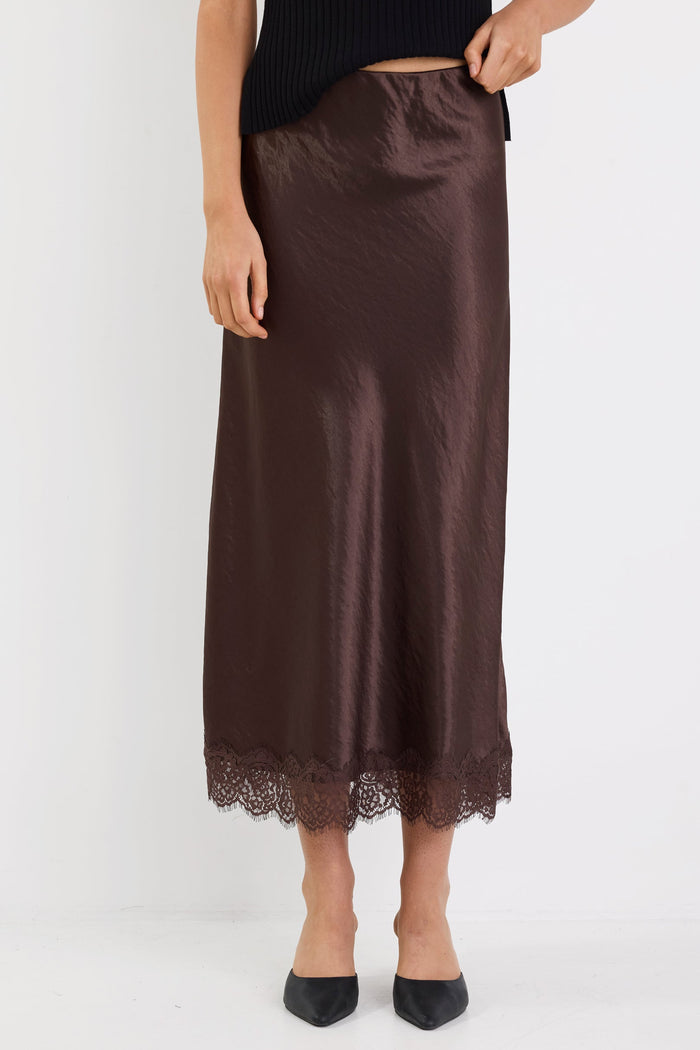 Brown satin skirt with lace hem worn by a person on a white background