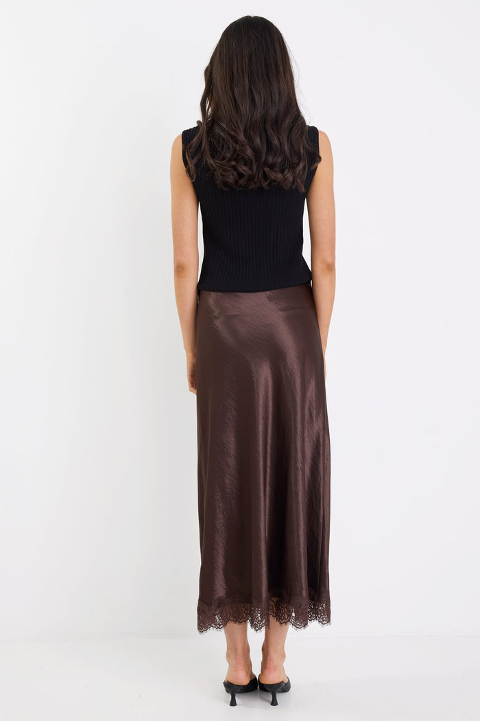 Woman wearing a black top and brown skirt on a white background