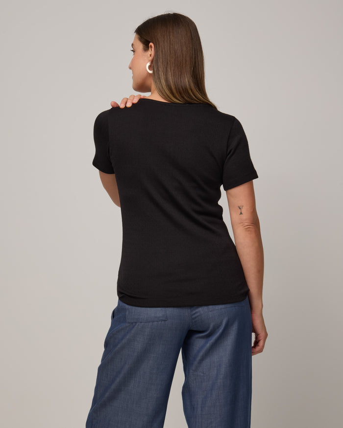 Model wearing Marie Pointelle Henley in Black. Marie Pointelle Henley is a short sleeve, scoop neck, fitted top available in sizes XS-3X.