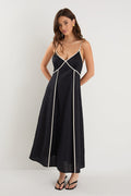 Woman wearing a black linen strappy dress with white contrast trim, fully lined, styled with black heeled sandals.