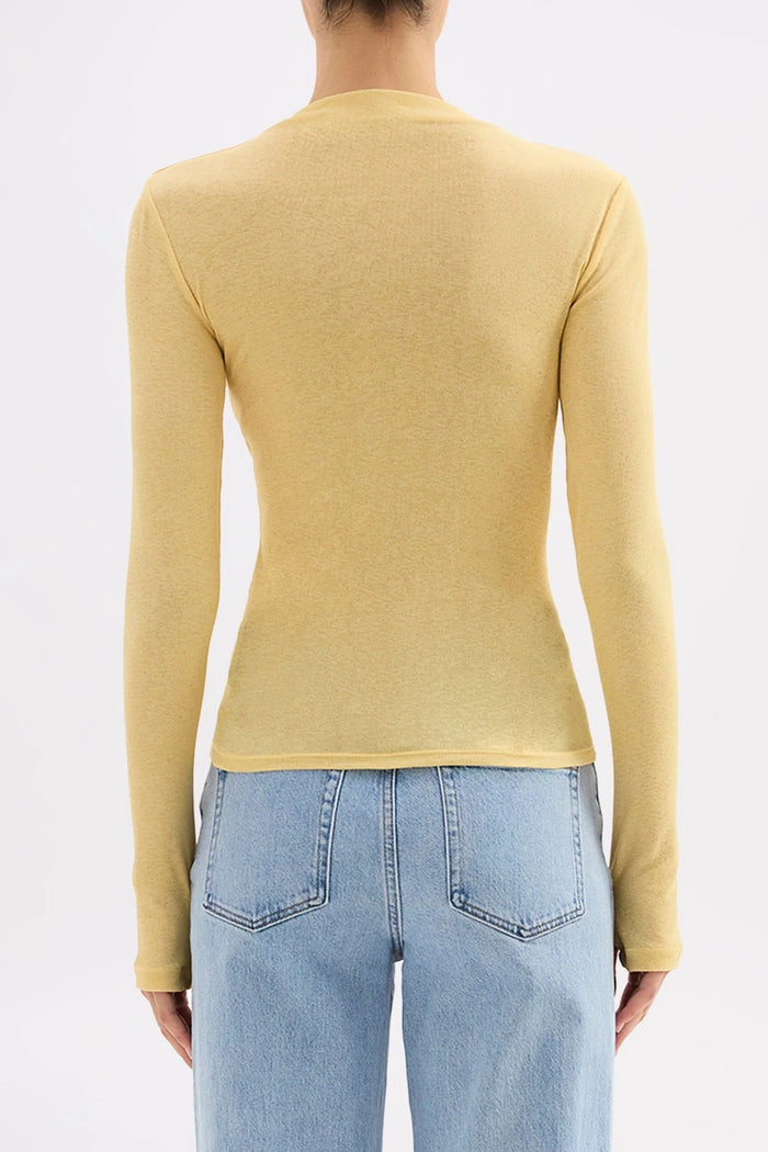 Person wearing a yellow long-sleeve top and light blue jeans on a white background