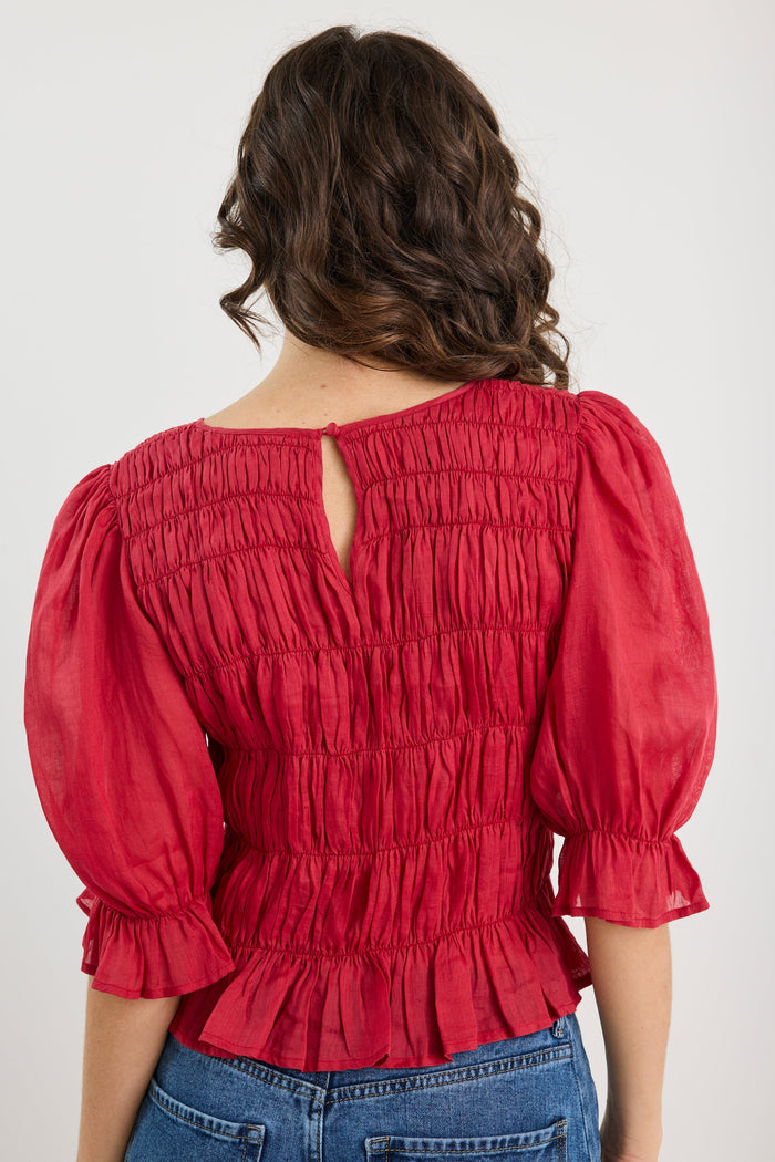 Red blouse with puff sleeves worn by a person on a white background