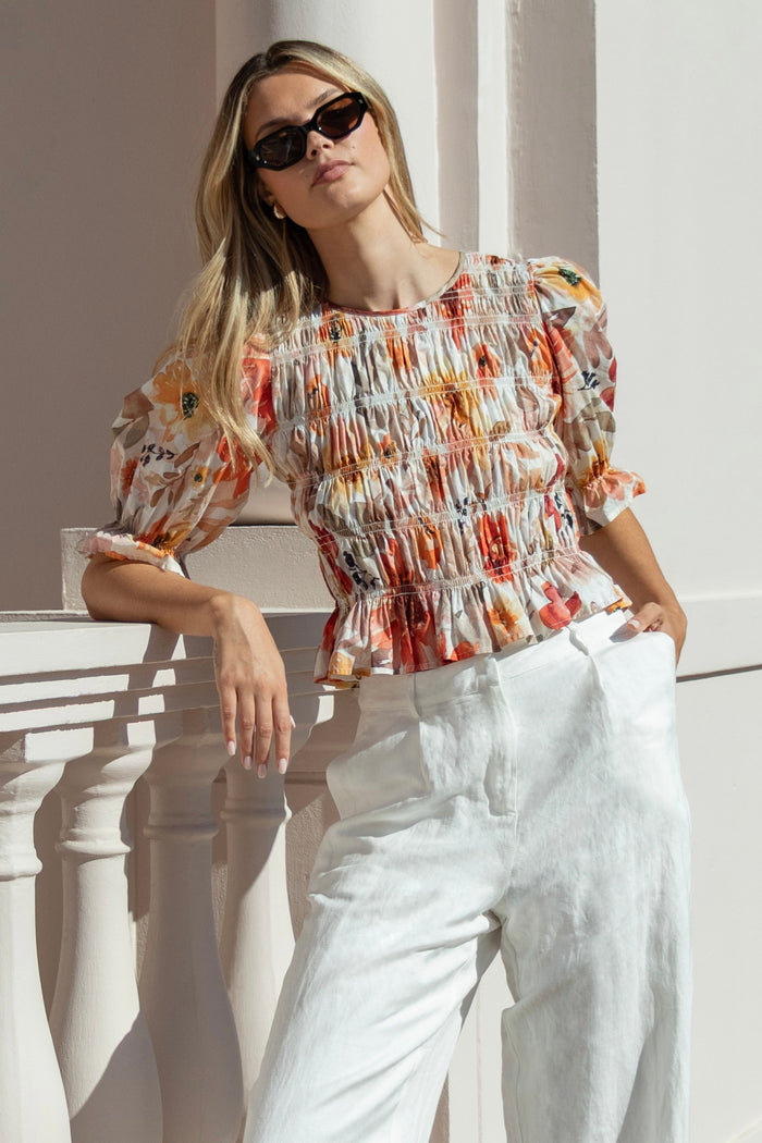 woman wearing a floral shirred short sleeve top with frill sleeves