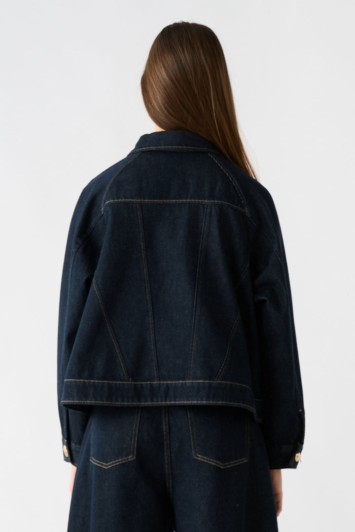 Person wearing a dark denim outfit on a white background