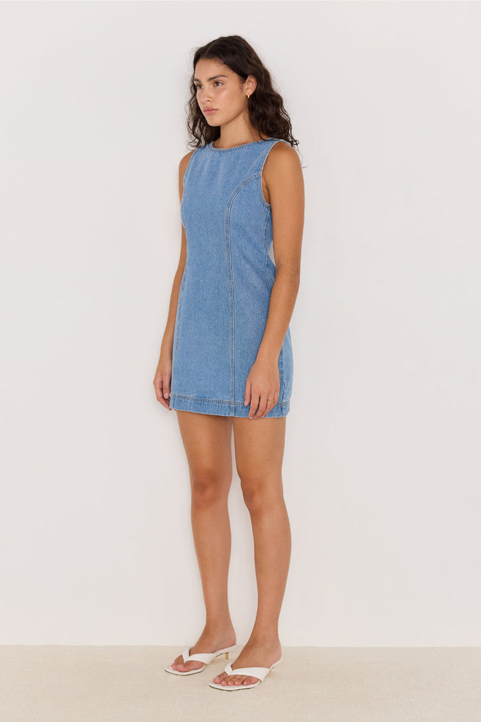 Woman wearing a blue denim dress against a white background