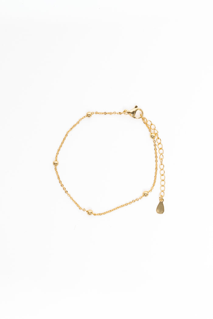 Gold bracelet with a teardrop charm on a white background