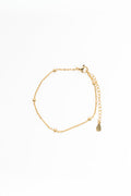 Gold bracelet with a teardrop charm on a white background