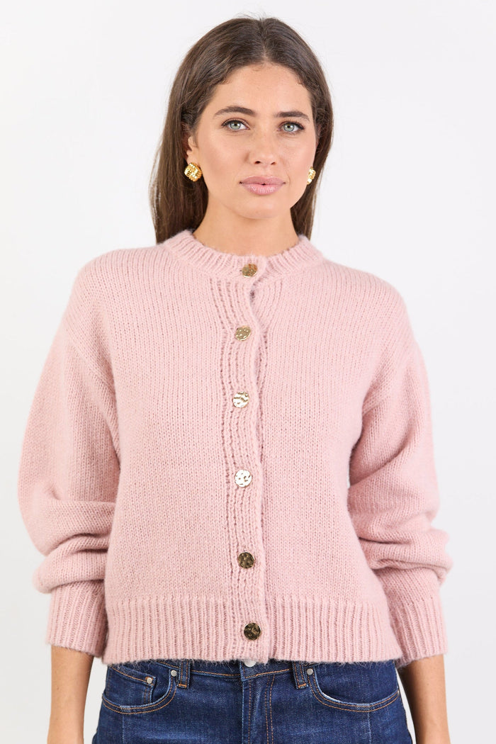 Woman wearing a pink cardigan with button details on a white background
