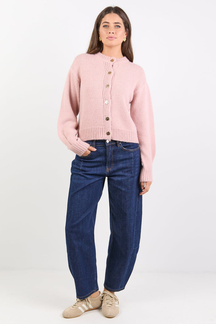 Women wearing pink cardigan and indigo jeans on white background.