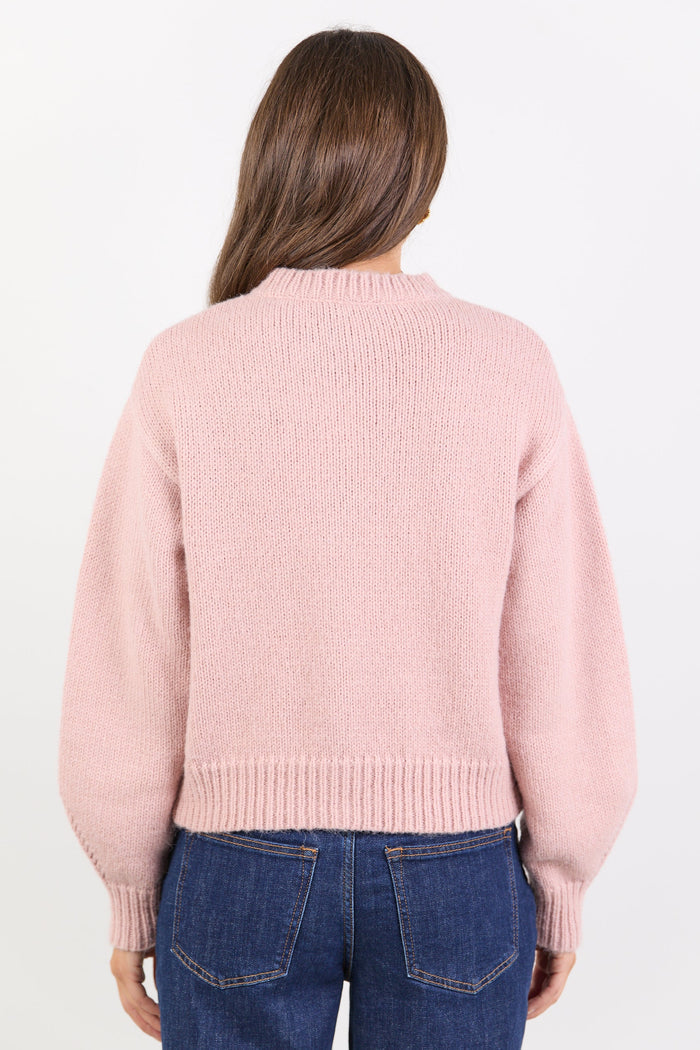 Person wearing a pink sweater and blue jeans on a white background