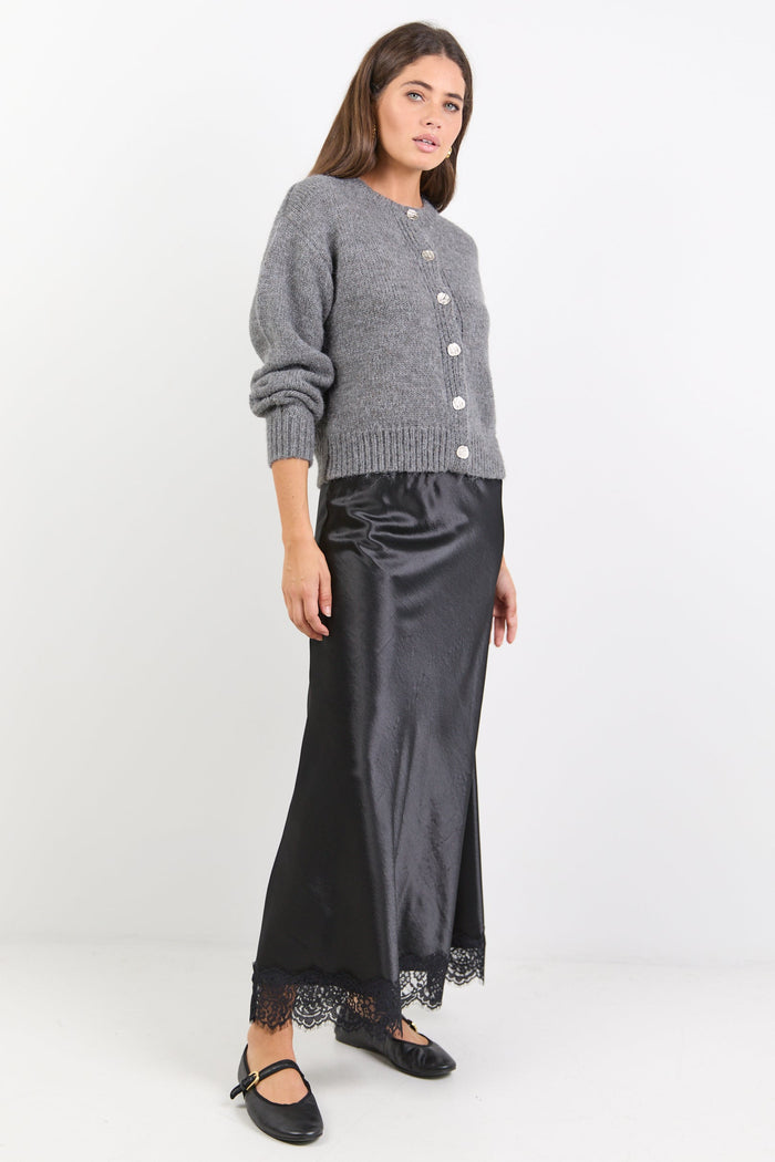 Woman wearing a gray cardigan and black skirt on a white background
