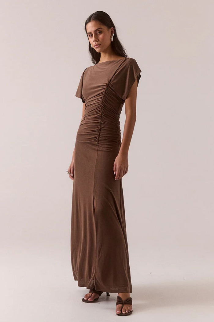 Woman wearing a brown ruched dress against a plain background