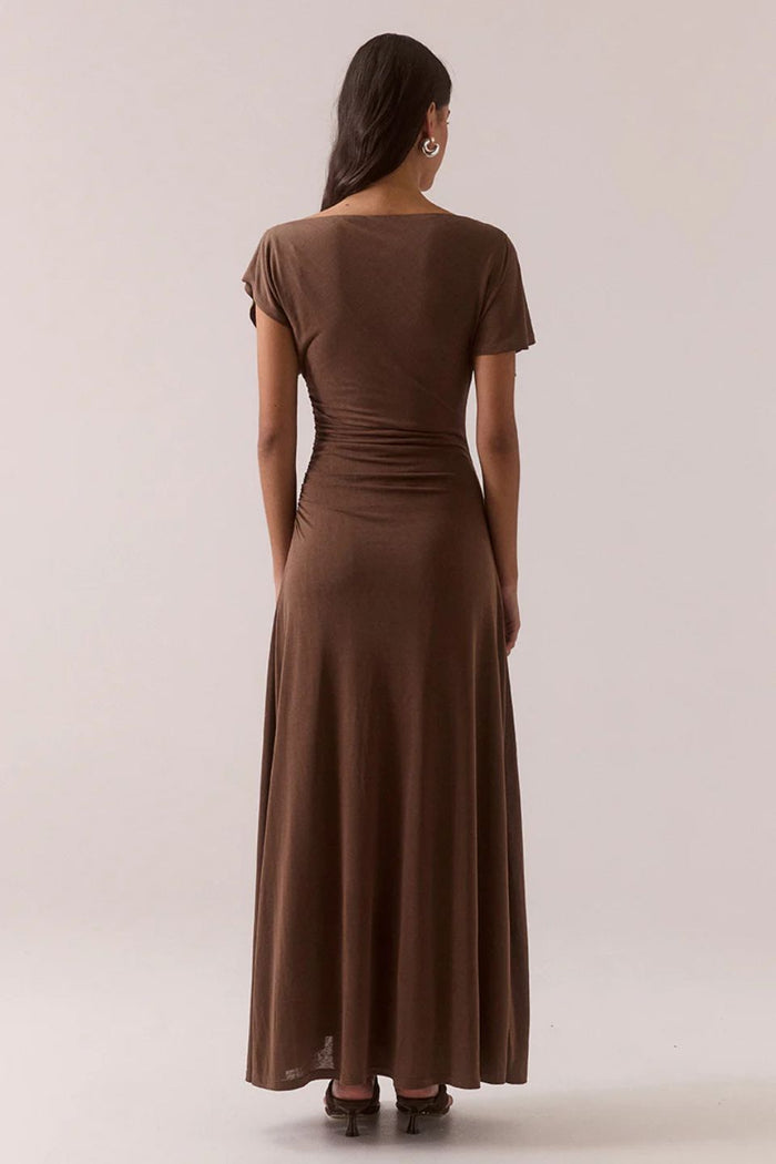 Woman wearing a brown dress against a plain background