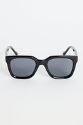 Glossy black rounded-square sunglasses with dark tinted lenses and RE:UNION label branding on the arm, photographed on a white background