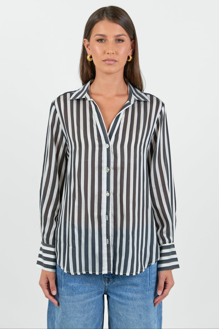 Woman wearing a black and white striped shirt with blue jeans on a white background
