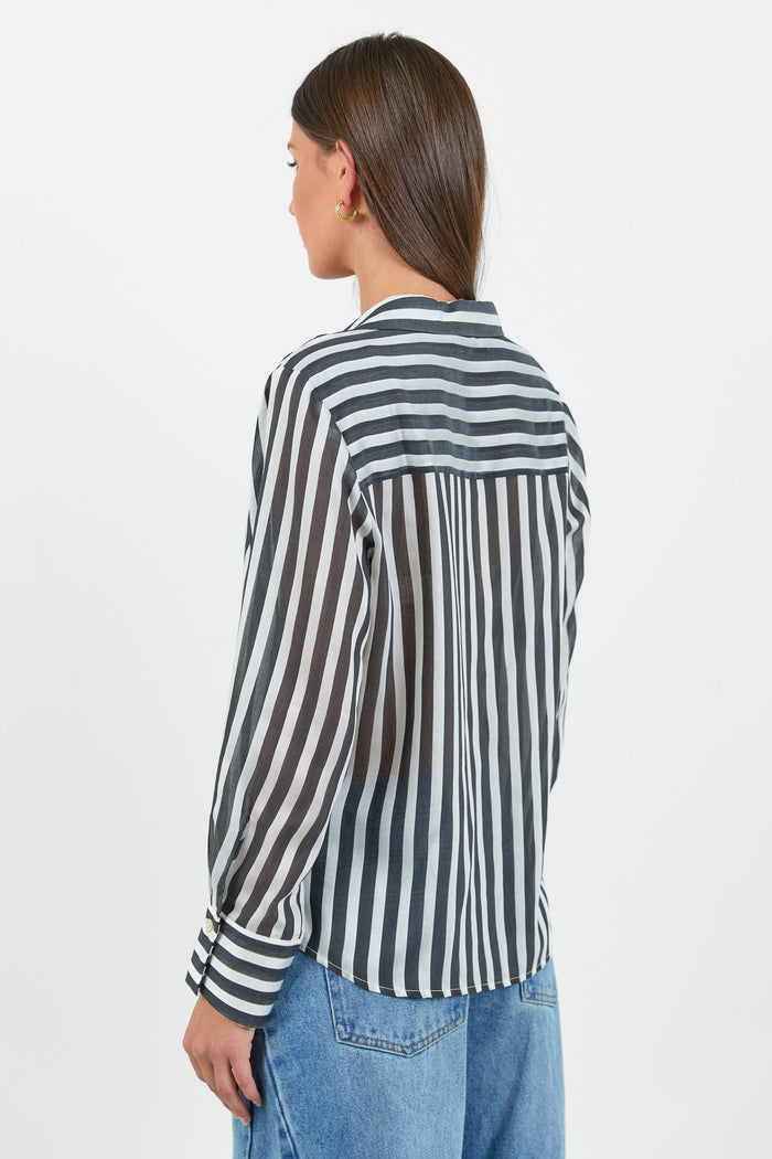 Person wearing a black and white striped shirt with blue jeans on a white background