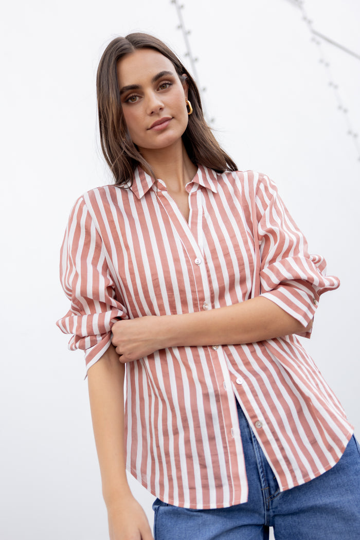 Woman wearing a red and white striped shirt with rolled-up sleeves against a white background