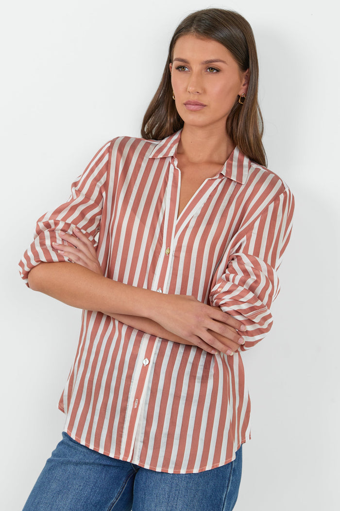 Woman wearing a striped shirt and jeans against a white background