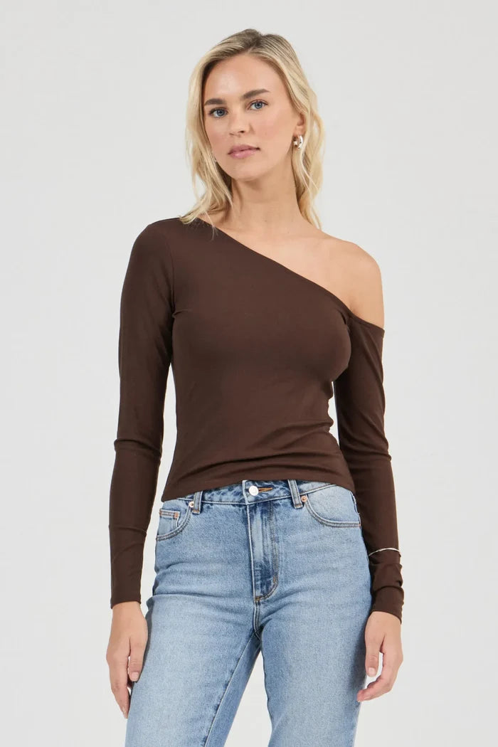Woman wearing a brown one-shoulder top and blue jeans on a white background
