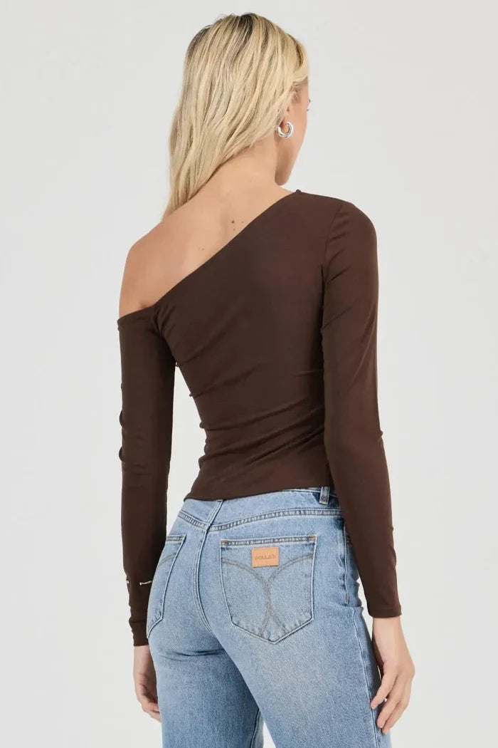 Woman wearing a brown long-sleeve top and light blue jeans on a white background