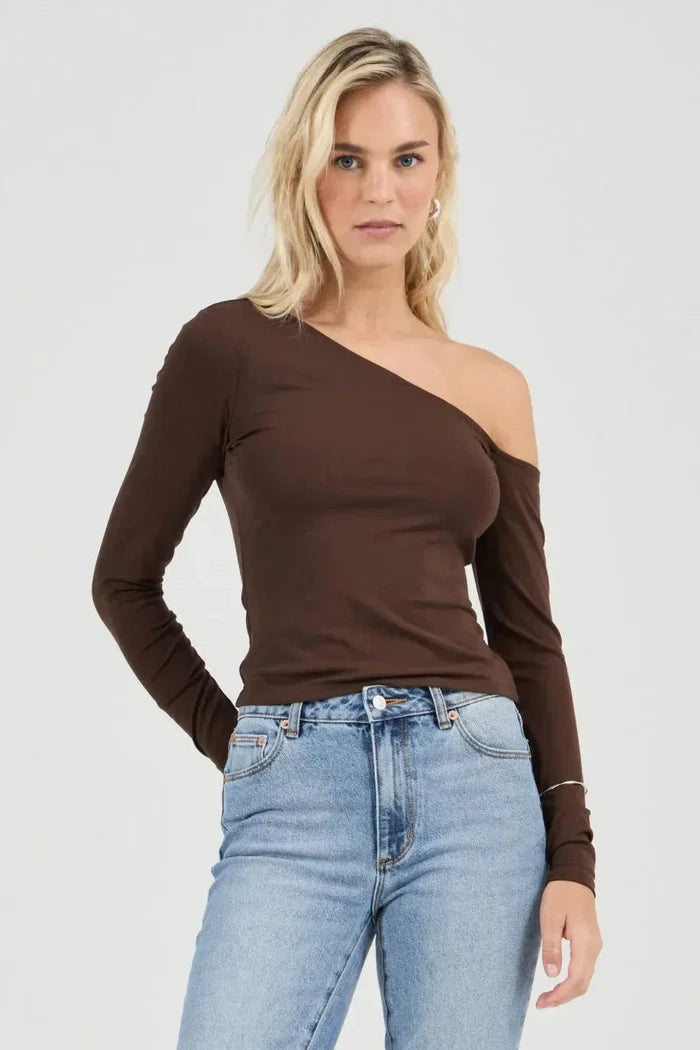 Woman wearing a brown one-shoulder top and light blue jeans on a white background