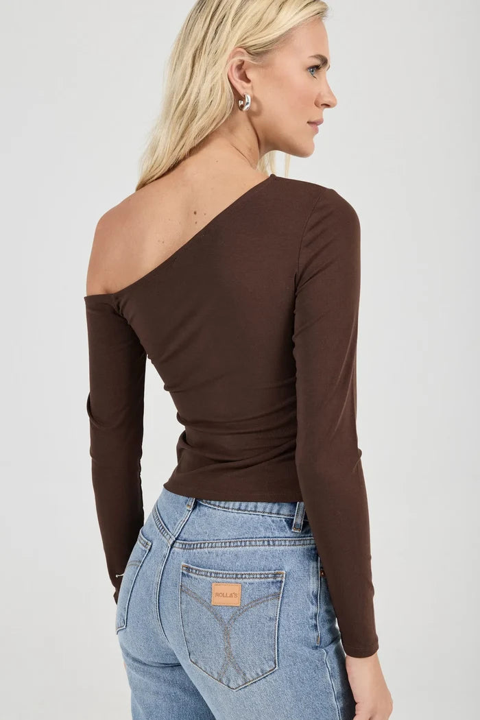 Woman wearing a brown one-shoulder top and blue jeans against a white background