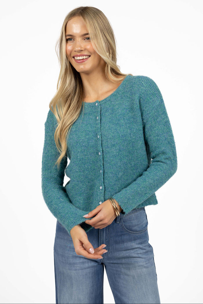 Woman wearing a teal cardigan and blue jeans on a white background