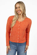 Woman wearing an orange knitted cardigan and blue jeans on a white background