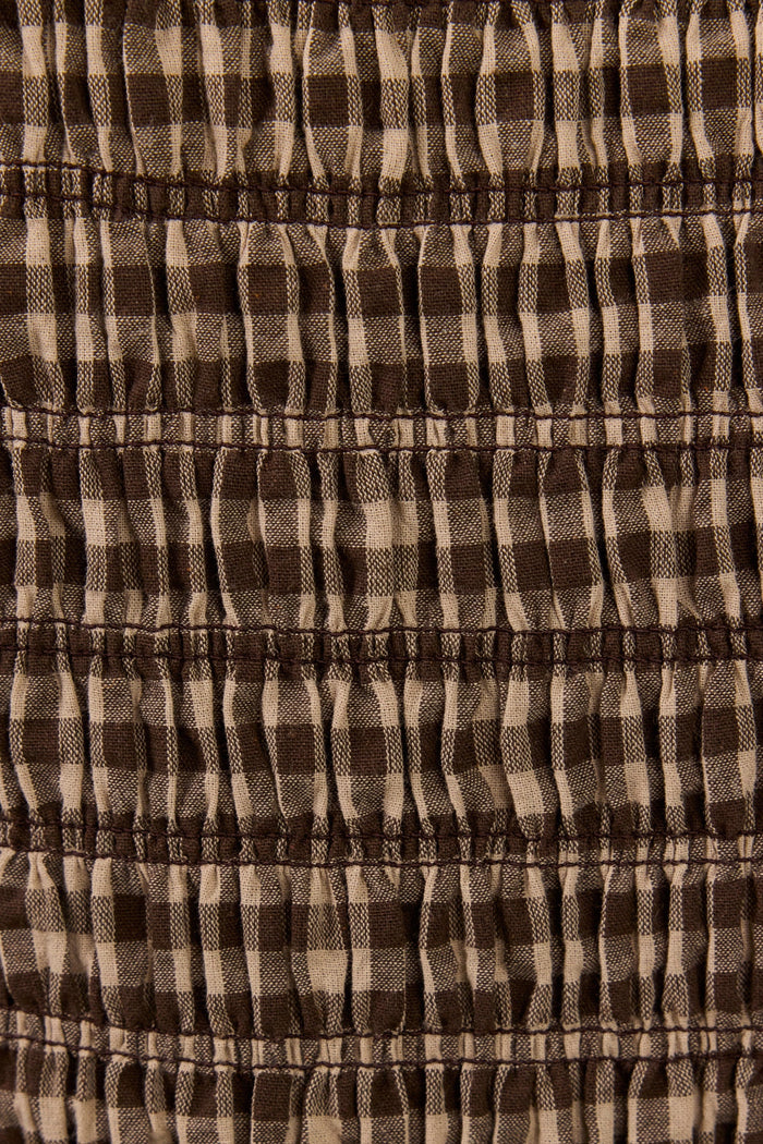 Close-up of a brown and beige gingham fabric with horizontal smocked or gathered stitching.
col_pattern