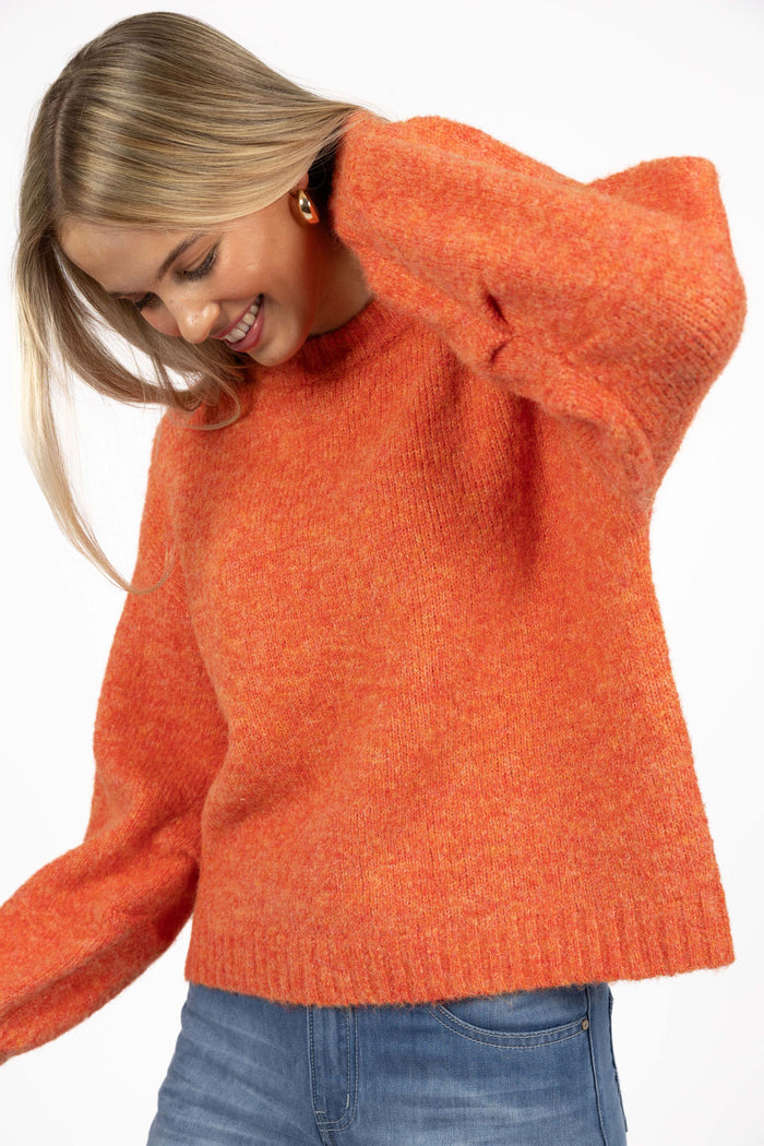 Woman wearing an orange sweater on a white background