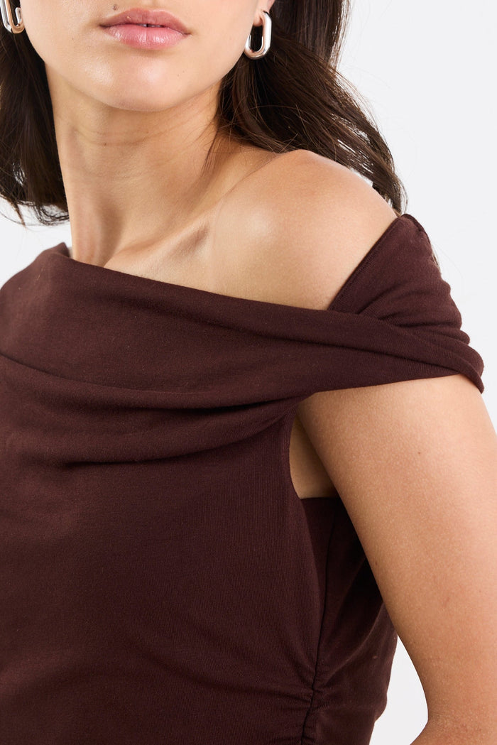 Woman wearing a brown off-shoulder top against a white background