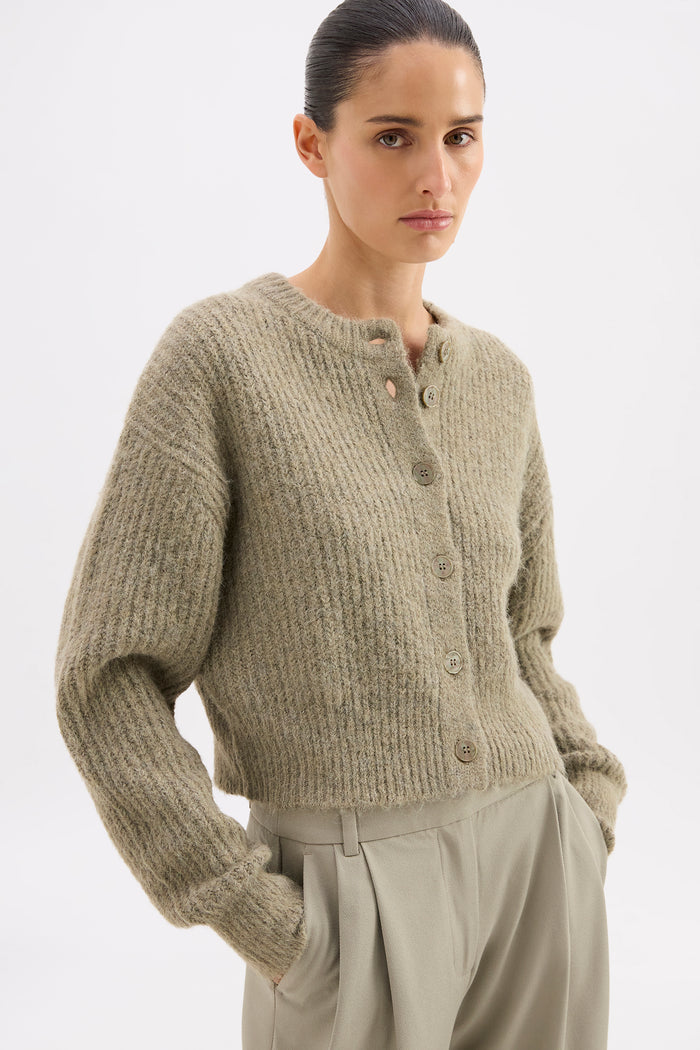 Woman wearing a beige knitted cardigan on a white background